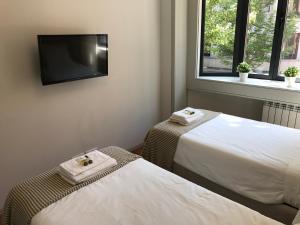 ポルトにあるLux Bolhão - ALL INCLUDEDのベッド2台、薄型テレビが備わる客室です。
