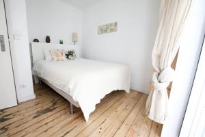 a white bedroom with a white bed and wooden floors at Alfama de Paixao in Lisbon
