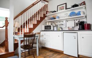 a kitchen with white cabinets and a table with a microwave at Salt Shaker Deli & Inn in Lunenburg