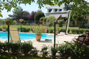 een hek rond een zwembad met twee stoelen bij Le Logis du Pressoir Chambre d'Hotes Bed & Breakfast in beautiful 18th Century Estate in the heart of the Loire Valley with heated pool and extensive grounds in Brion