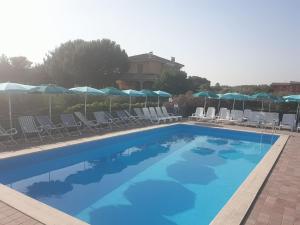 a large swimming pool with chairs and umbrellas at Villa Milici in Campobello di Licata