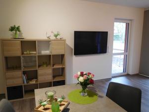a living room with a table and a tv on the wall at Ferienwohnung Kurpark in Xanten