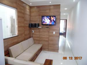 een woonkamer met een bank en een tv aan de muur bij Propriedade Silva in Gamboa