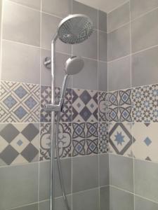 um chuveiro numa casa de banho com azulejos azuis e brancos em Un petit nid a Honfleur em Honfleur