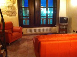 a living room with an orange chair and a tv at Residence LA FORTUNA in Fano