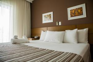 a hotel room with a large bed with white pillows at Mundial Parque Hotel in Viçosa +27 photos