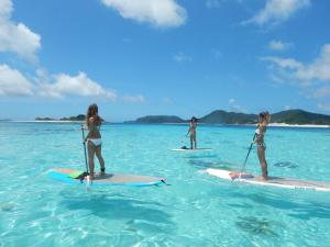 three women are standing on surfboards in the ocean at Oceans Cottage in Nago