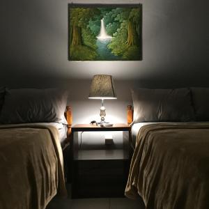 a room with two beds and a table with a lamp at Cempaka Homestay in Uluwatu +10 photos