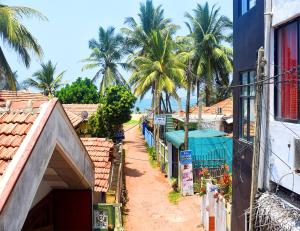 a dirt road between two buildings with palm trees at Sun Rise Hostel in Negombo