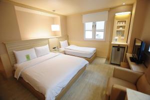 a hotel room with two beds and a television at Kindness Hotel - Jhong Jheng in Kaohsiung