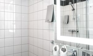 a white tiled bathroom with a sink and a mirror at Thon Hotel Europa in Oslo