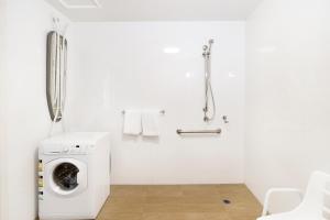 a white bathroom with a washing machine in it at Abode Gungahlin in Canberra