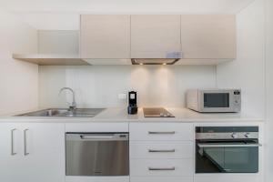 a white kitchen with a sink and a microwave at Abode Tuggeranong in Canberra