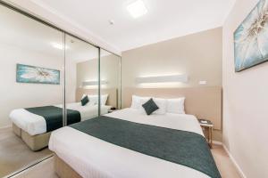 a hotel room with two beds and a mirror at Abode Tuggeranong in Canberra