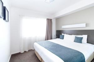 a bedroom with a large bed and a window at Abode Tuggeranong in Canberra