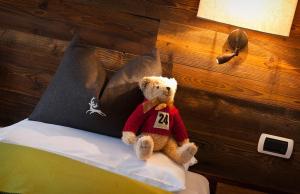 a teddy bear sitting on top of a bed next to a lamp at Hotel Andreas Hofer in Brunico