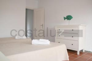 a white bedroom with a bed and a dresser at Apartamentos Aguadulce El Portil in El Portil