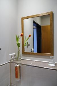 a bathroom with a mirror and a vase with flowers at Bei Meier`s zum weißen Roß in Königslutter am Elm +25 photos