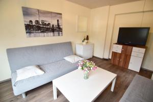 ein Wohnzimmer mit einem Sofa, einem TV und einem Tisch in der Unterkunft Work & Stay Ferienhaus Niederkassel in Rheidt
