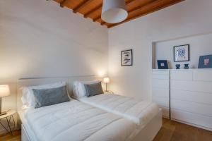 a white bedroom with a large white bed with two pillows at Apartments Florence - Fortezza in Florence