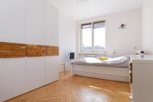 a white bedroom with a bed and a window at Apartament Libelta in Poznań