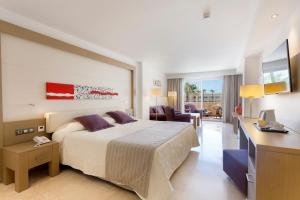 a hotel room with a large bed and a desk at Hipotels Playa La Barrosa - Adults Only in Chiclana de la Frontera