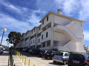 a large white building with cars parked in a parking lot at Isla Apart in Sitges