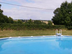 einen Pool mit Blick auf ein Feld und Bäume in der Unterkunft La Metairie in Parthenay