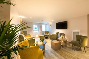 Una sala de espera con sillas y mesas y un televisor de pantalla plana. en Villa Bettina, en La Baule