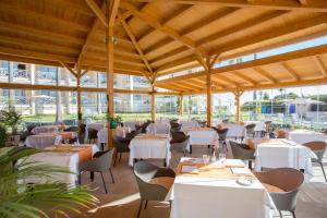 a restaurant with white tables and chairs and windows at Hipotels Playa La Barrosa - Adults Only in Chiclana de la Frontera