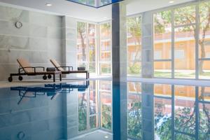 a room with a pool with two chairs and windows at Hipotels Playa La Barrosa - Adults Only in Chiclana de la Frontera