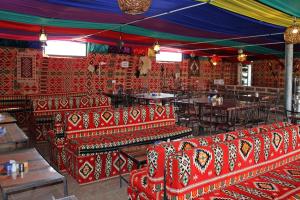un restaurant avec des chaises et des tables rouges dans une salle dans l'établissement Seven Wonders Bedouin Camp, à Wadi Musa
