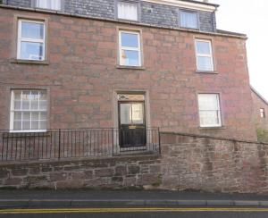 um edifício de tijolos com uma porta e uma varanda em The Gallery Flat, 4 Tannage Brae em Kirriemuir