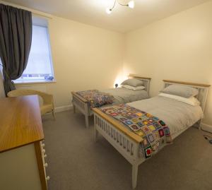 a bedroom with two beds and a window at The Gallery Flat, 4 Tannage Brae in Kirriemuir