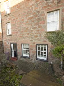 a brick building with three windows and a door at The Gallery Flat, 4 Tannage Brae in Kirriemuir