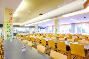 a large lecture hall with tables and yellow chairs at HI Munich Park Youth Hostel in Munich