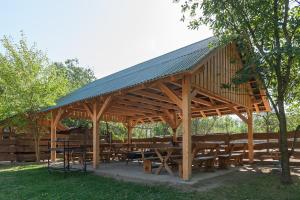 a large wooden pavilion with wooden tables and benches at Páratlan Apartmanház in Szilvásvárad