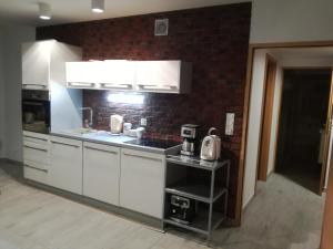 a kitchen with white cabinets and a brick wall at Willa na klifie in Rewal