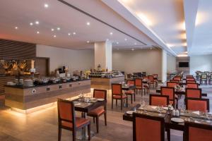 ein Restaurant mit Tischen und Stühlen und eine Bar in der Unterkunft Concorde Hotel Doha in Doha