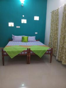 a small bed in a room with a green wall at Angelann Homestay in Cochin