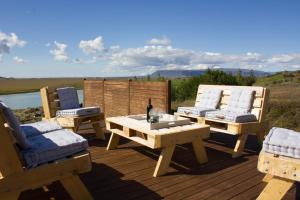 a wooden deck with two chairs and a table with a bottle at GreenKey Paradise Cabin in Selfoss