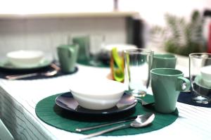 uma mesa com pratos verdes, copos e colheres em Swell Guesthouse em Casa Moinho