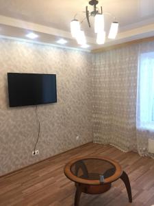 カザンにあるApartment on Nikolaya Yershovaのリビングルーム(テーブル、壁掛けテレビ付)
