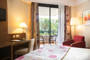 Habitación de hotel con cama, escritorio y ventana en Hipotels Sherry Park, en Jerez de la Frontera