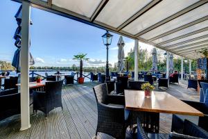 a restaurant with tables and chairs on a deck at Vesting de Bronsbergen in Zutphen