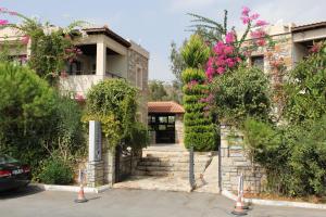 una casa con una puerta y algunos arbustos y flores en Villanaz Apart Hotel, en Bitez
