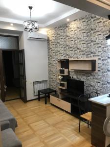 sala de estar con pared de ladrillo y TV en Kaskad apartment and Tours, en Ereván