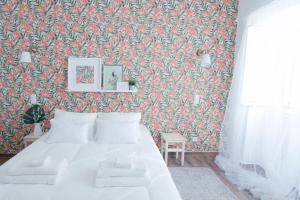 ein Schlafzimmer mit einem weißen Bett mit Blumentapete in der Unterkunft Casas de Mar - Concha in Olhão + 13 Fotos