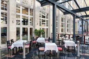 a restaurant with white tables and chairs and windows at Wyndham Garden Berlin Mitte in Berlin