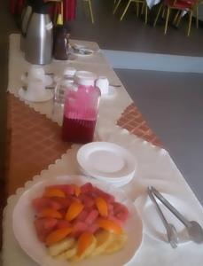 une assiette de fruits et une boisson sur une table dans l'établissement Mt. Zion Hotel Annex, à Kampala